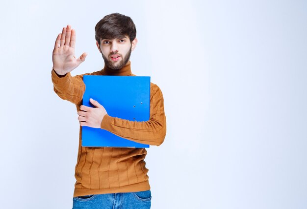 Homme avec un dossier bleu arrêtant quelque chose.