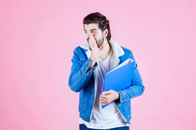 Homme avec un dossier bleu chuchotant et bavardant