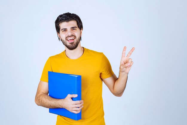 Homme avec dossier bleu donnant des poses amicales et paisibles.