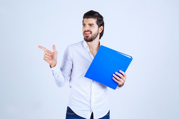 Homme avec un dossier bleu présentant son collègue à gauche