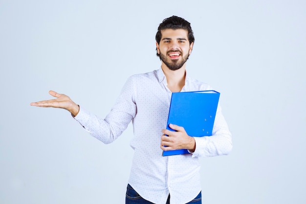 Homme avec un dossier bleu présentant son collègue à gauche