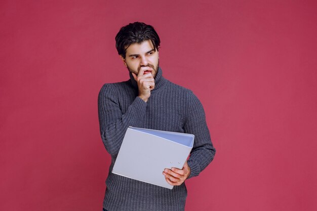 L'homme avec le dossier gris a l'air pensif.