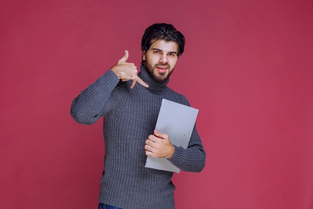 Homme avec dossier gris demandant à le contacter.