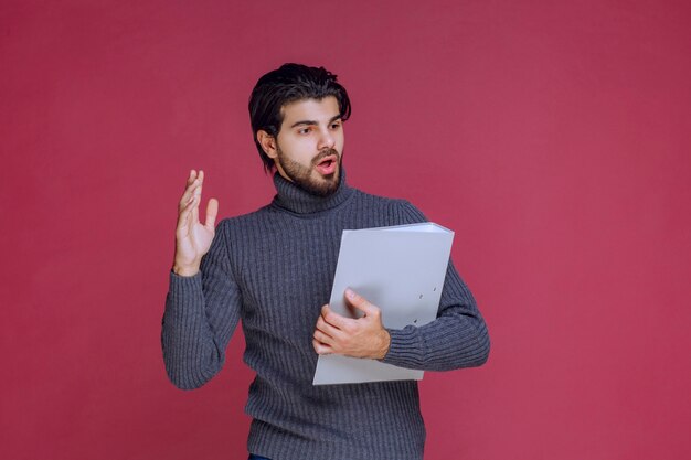 Homme avec dossier gris en discutant avec les collègues lors de la vérification.