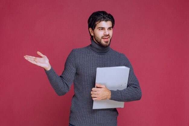 Homme avec dossier gris en discutant avec les collègues lors de la vérification.