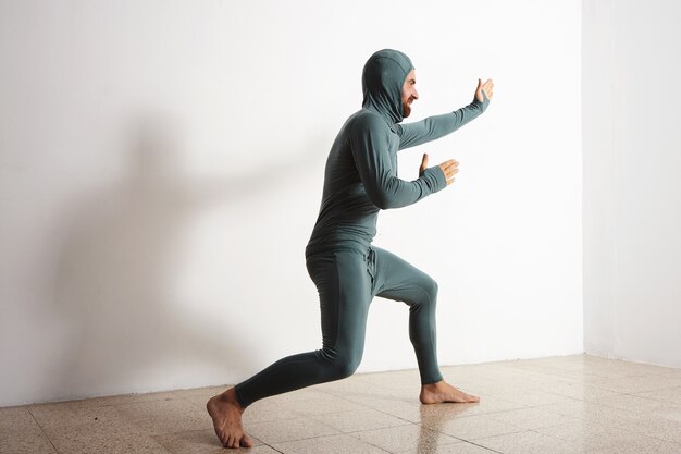 Homme drôle barbu pose comme un ninja portant sa suite thermique de sous-couche thermique, isolé sur blanc
