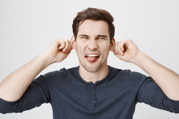 Homme drôle enfantin tirant les oreilles et montrant la langue, grimaçant