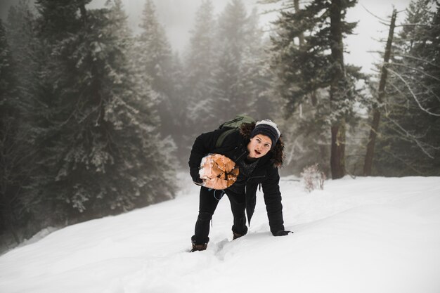 Homme avec du bois de chauffage marchant sur la neige