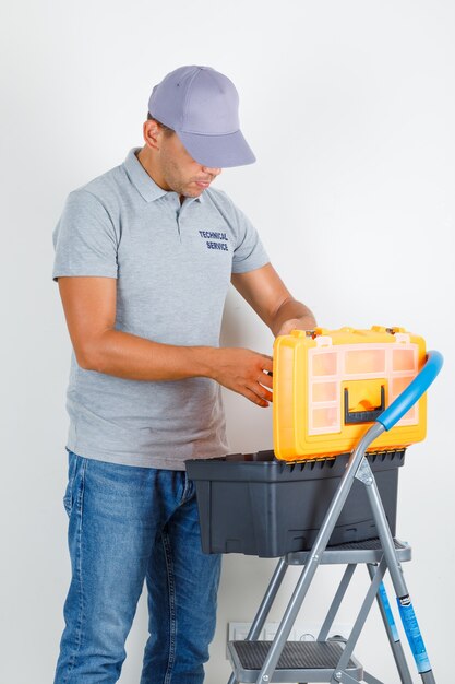 L'homme du service technique à la boîte à outils en t-shirt gris avec capuchon et à occupé