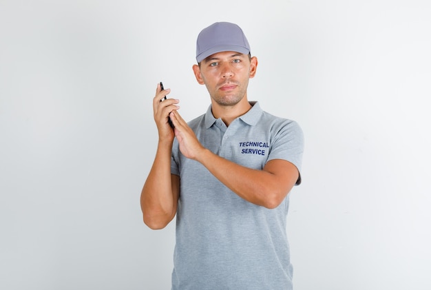 Homme du service technique en t-shirt gris avec capuchon couvrant le microphone sur smartphone
