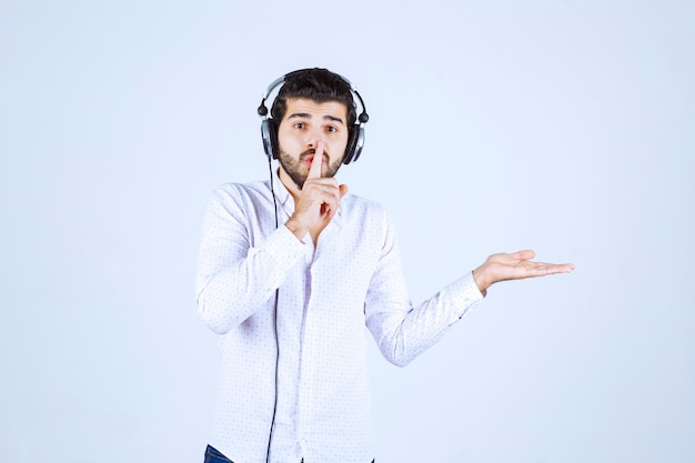 Homme avec des écouteurs demandant le silence.