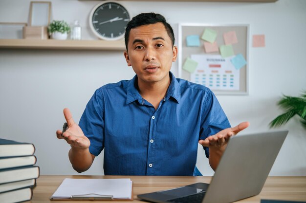 Homme avec des écouteurs travaillant au bureau avec des papiers et un ordinateur portable sur le bureau