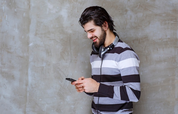 Homme Avec Des écouteurs Vérifiant Ses Messages Ou Sa Liste De Lecture Musicale Avec Une énergie Positive