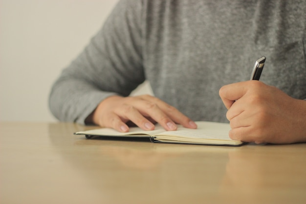 Homme écrivant sur son cahier avec un stylo noir