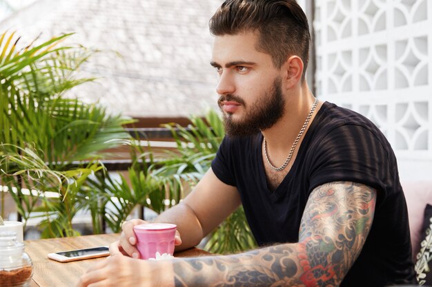 Homme élégant barbu assis dans un café