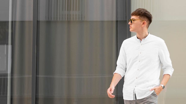 Photo gratuite homme élégant avec des lunettes de soleil posant à l'extérieur avec espace copie