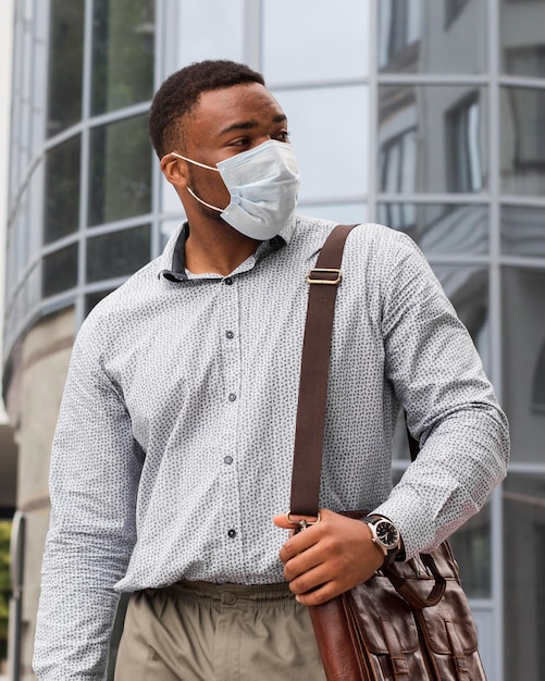 Homme élégant avec masque facial sur le chemin du travail pendant la pandémie