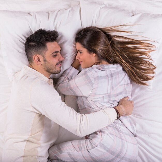 Homme embrassant une femme au lit