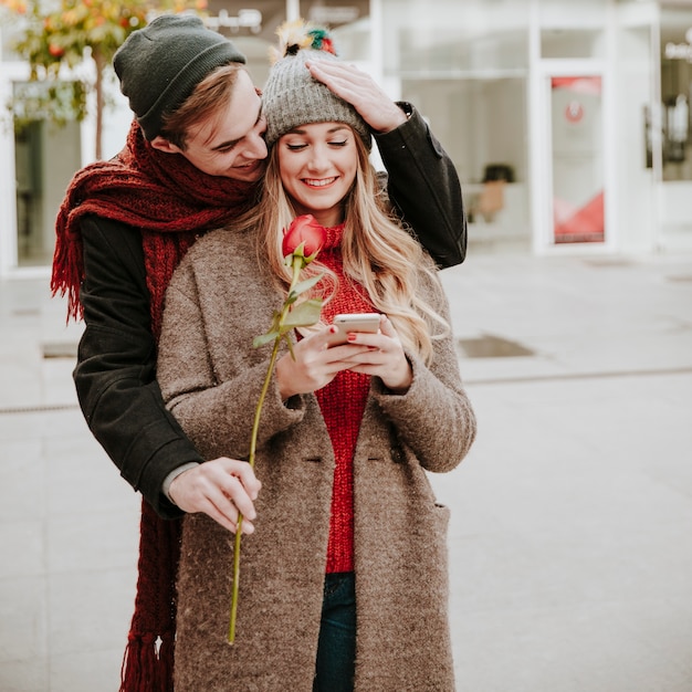 Homme embrassant la femme et donnant rose