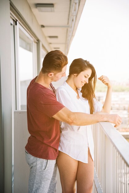 Homme embrassant une femme par derrière sur un balcon