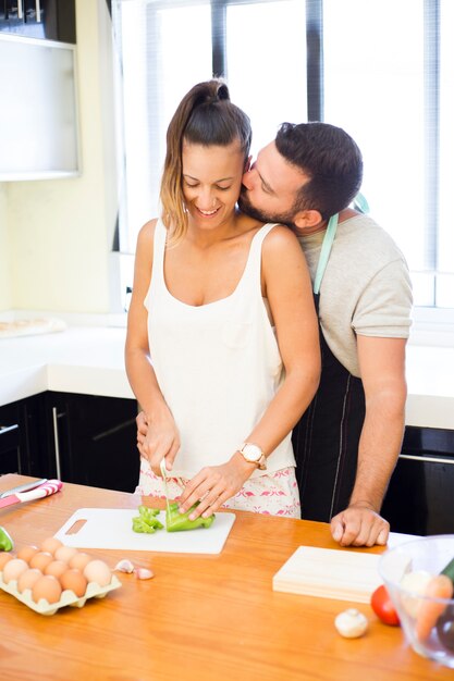 Homme embrassant sa femme pendant la préparation de la nourriture dans la cuisine