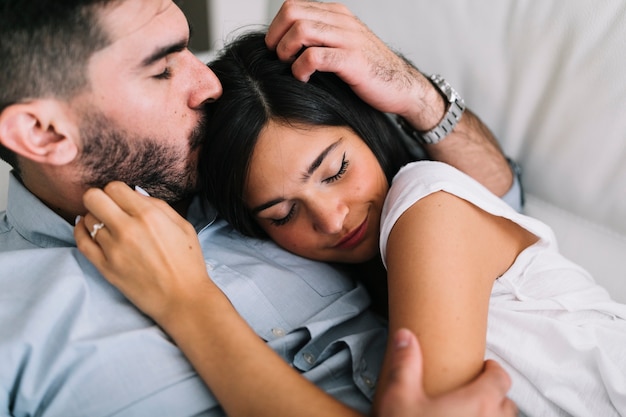 Homme embrassant la tête de sa copine en train de dormir avec lui