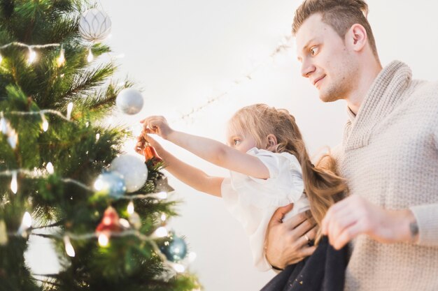 Homme et enfant décorer ensemble sapin de Noël illuminé