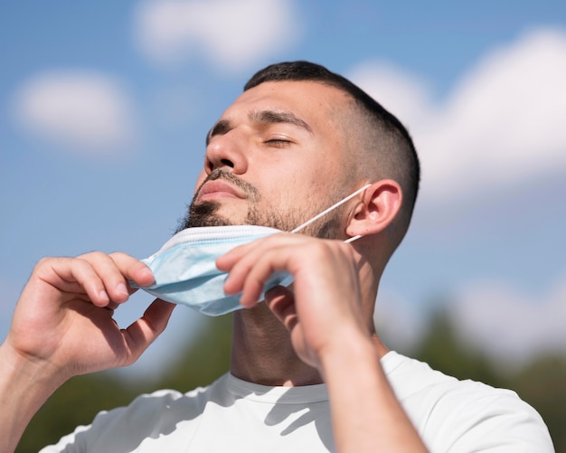 Homme enlevant son masque médical