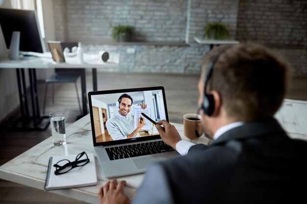 Homme entrepreneur utilisant un ordinateur portable lors d'une réunion en ligne et parlant à son collègue de rapports d'activité L'accent est mis sur l'écran d'un ordinateur portable