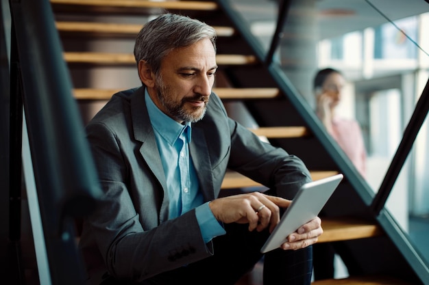 Homme entrepreneur utilisant une tablette numérique assis sur un escalier