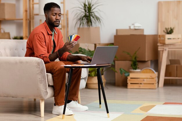 Photo gratuite l'homme envisage de redécorer la maison à l'aide d'une palette de couleurs et d'un ordinateur portable