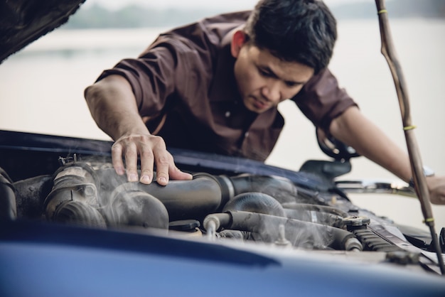 Homme essayant de réparer un problème de moteur de voiture sur une route locale