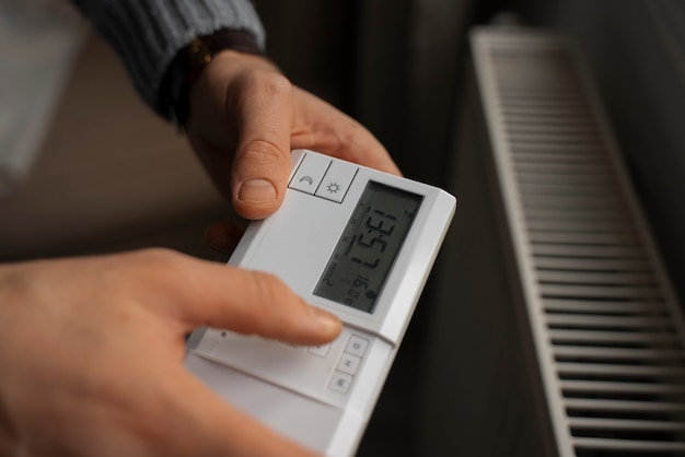 Homme éteignant le thermostat pendant la crise énergétique