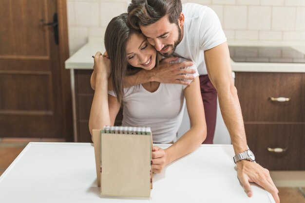 Homme étreignant petite amie avec le bloc-notes