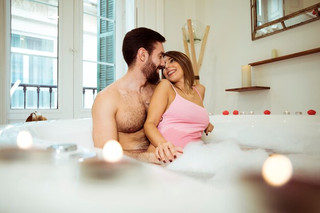 Homme, étreindre, femme souriante, dans, baignoire spa, à, eau mousse