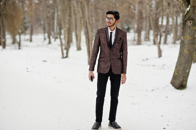 Homme étudiant indien élégant en costume marron et lunettes posées à la journée d'hiver en plein air