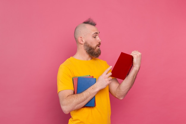 Homme européen barbu avec pile de livres sur rose