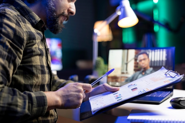 Photo gratuite un homme examine des documents lors d'un appel vidéo