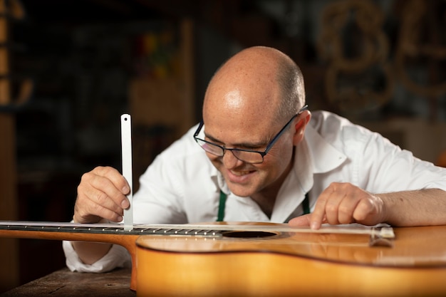 Photo gratuite homme fabriquant des instruments dans son atelier