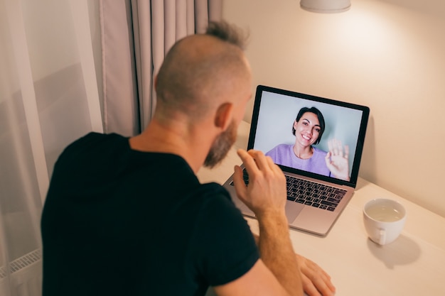 Homme facetime à la maison, appelant sa copine amie de son ordinateur portable dans la chambre.