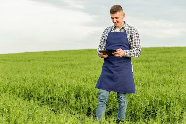 Homme faible angle à la ferme avec tablette