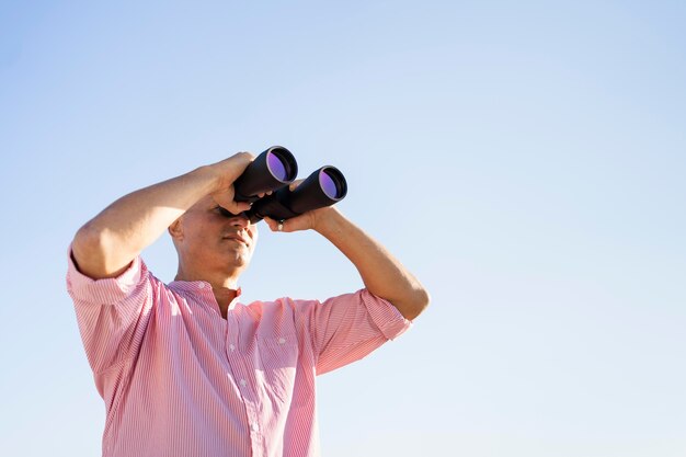 Homme de faible angle regardant à travers des jumelles