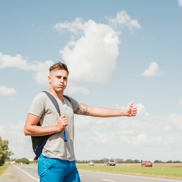 Homme faisant de l'auto-stop sur une route