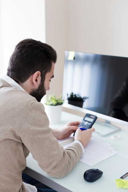 Photo gratuite homme faisant des calculs au bureau