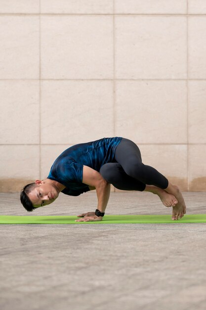 Homme faisant du yoga en plein air sur tapis