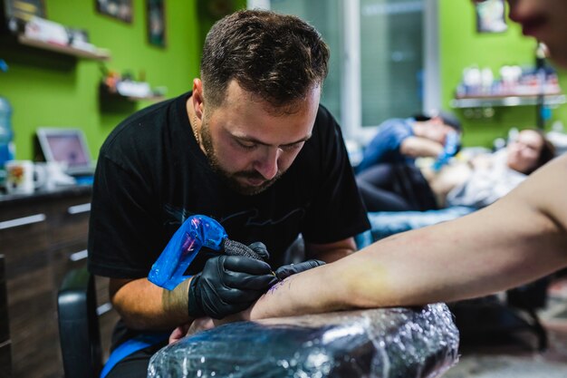 Homme faisant le tatouage sur le bras dans le salon