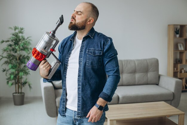 Homme faisant le travail de maison avec l'aspirateur d'accumulateur