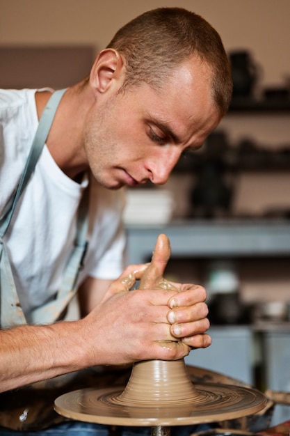 Photo gratuite homme faisant la vue de côté de poterie