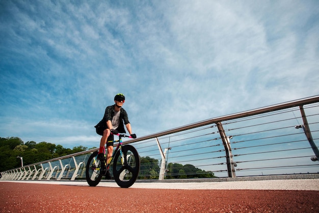 Photo gratuite l'homme fait du vélo au pontl'image du cycliste en mouvement sur le fond le matin