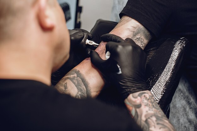 Homme fait un tatouage dans un salon de tatouage